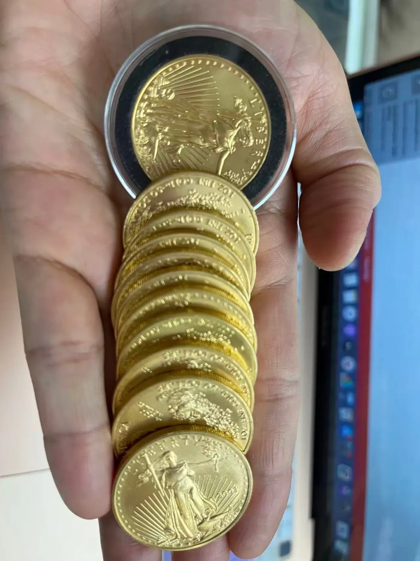 Stack of 1 oz American Gold Eagle bullion coins held in hand at TWG Cash for Gold